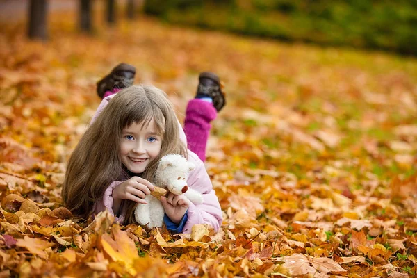 Cute little girl lie on the autumn leaves — Stock Photo, Image