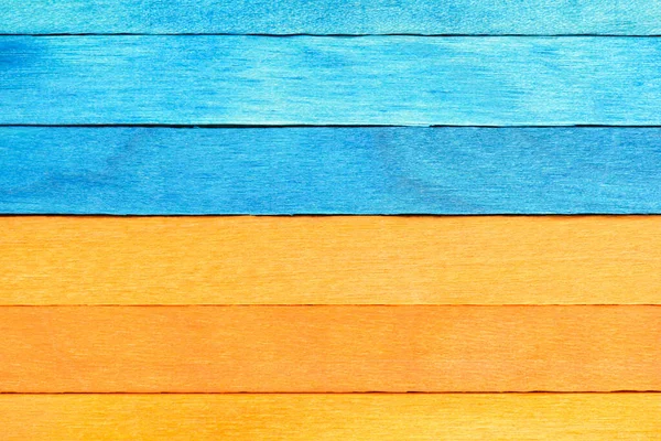 Bicolor background from blue and orange wooden planks. Wooden textured background with natural patterns. Orange and Blue painted wooden boards arranged horizontally.