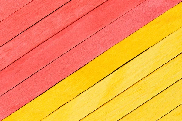 Bright yellow and red painted boards arranged diagonally. Wooden textured background. Textured straight planks in red and yellow.