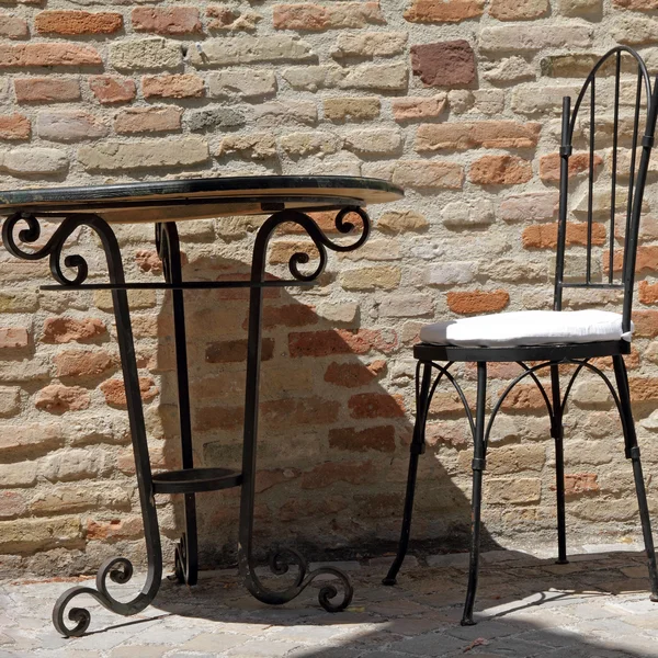 Επεξεργασμένου σιδήρου καρέκλα και ένα τραπέζι στην ηλιόλουστη βεράντα — Φωτογραφία Αρχείου