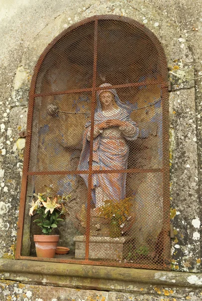 Svatyně madonna postava a lily v hrnci ve výklenku na zeď — Stock fotografie
