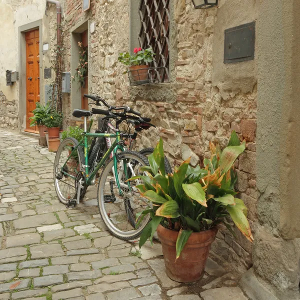 Geparkeerde bikes op steen oude Toscaanse straat — Stockfoto