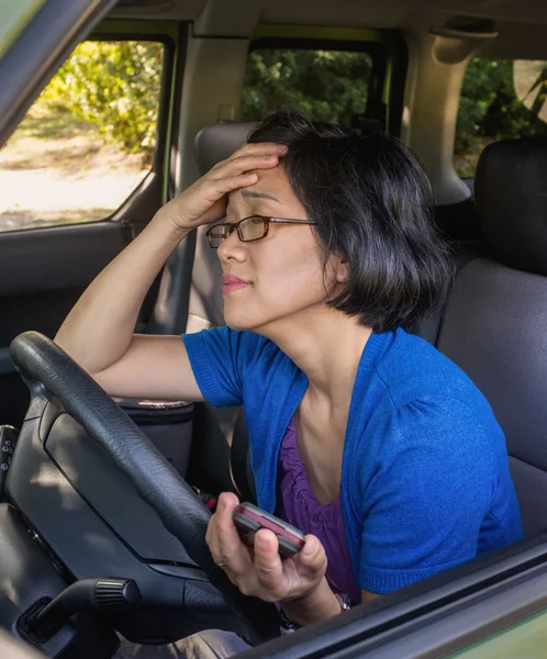 Frustrerad kvinna i bil i bilkö håller mobilen — Stockfoto