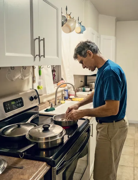 Candid Foto de um homem maduro cozinhar jantar para um — Fotografia de Stock