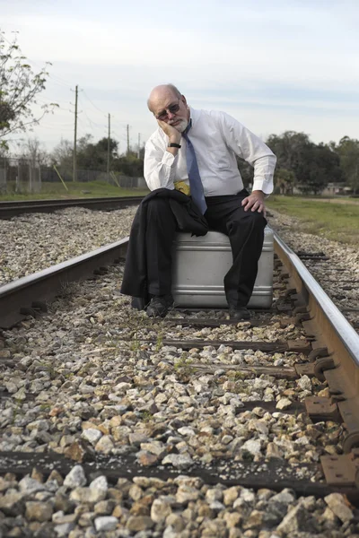 Tired Jobless senior businessman sits on suitcase on railroad train tracks — Stock Photo, Image