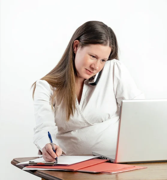 Pregnant Young Woman on Phone at Laptop at Work or Home Stock Picture