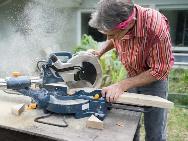 Mann sägt Holz mit verschiebbarer Gehrungssäge — Stockfoto