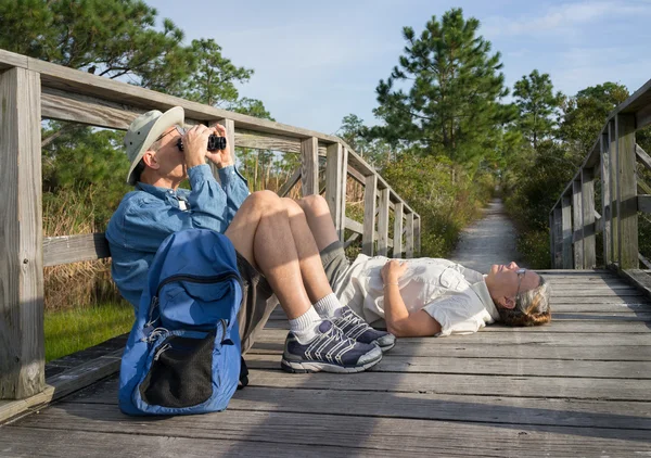 Senioren birdwatching en ontspannen op oude houten voetgangersbrug — Stockfoto