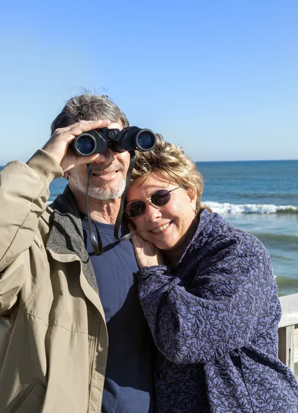 Jubilados pareja de ancianos en Florida vacaciones en la playa abrazos y observación de aves — Foto de Stock