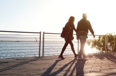 Gün batımında ticari limanda yürüyen sevgi dolu bir çift. Aşk kavramı.