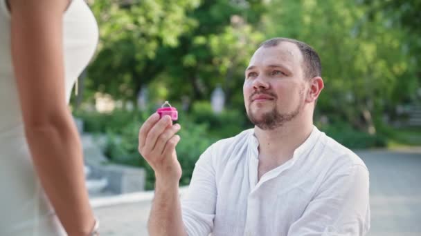 Portrait d'un homme joyeux avec un anneau dans ses mains demande en mariage à sa bien-aimée en s'agenouillant, épouse-moi — Video