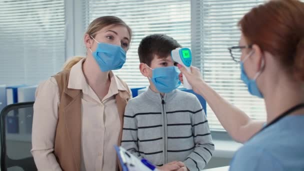 Läkare samråd, familj bär skyddsmasker i receptionen lyssna på terapeut på sjukhuset närbild — Stockvideo