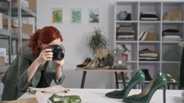 Küçük işletme, DSLR kameralı gülümseyen genç bir kadın internet sitesi ve butik dükkanının sosyal ağları için malların fotoğrafını çekiyor