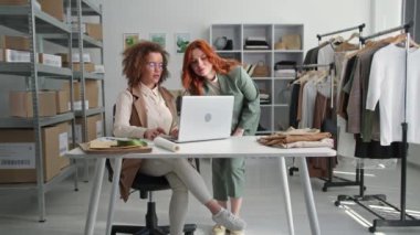 Çevrimiçi mağazada çalışmak, genç bayan çalışanlar dizüstü bilgisayarda alışveriş yapanlar için kontrol etmek moda butiğinde oturmak.