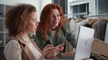 Küçük işletmeci genç çekici kadınlar bir mağazada çalışıyor ve mağazadaki depoda oturan müşterilere alım satımlarını ayarlamak için dizüstü bilgisayar kullanıyorlar.