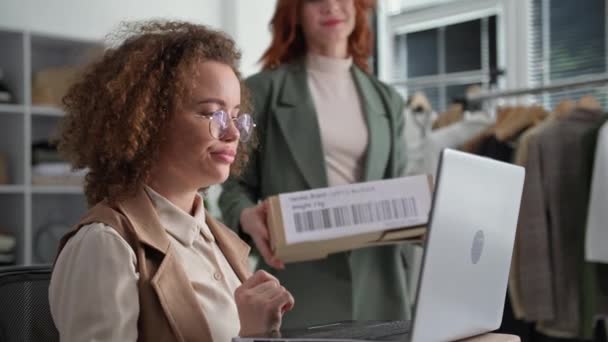 Boutique online, jovem mulher pequena empresária, juntamente com o empregado feminino organizar a entrega de encomendas on-line na loja de roupas — Vídeo de Stock