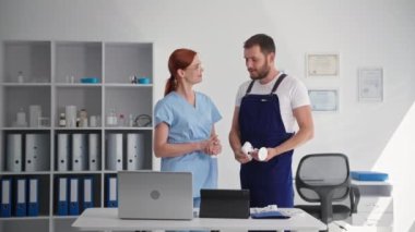 Üniformalı genç adam, çalışma odasına video izleme sistemi yerleştirerek, tıbbi odasındaki gizli güvenlik kamerası ve uygulamayı açıklıyor.