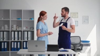 Görsel kontrol, erkek güvenlik görevlisi üniformalı genç bir bayana güvenlik kamerasının ve tıbbi ofisin işleyişini anlatıyor.