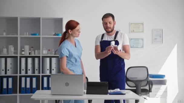 Bezpečnost prostor, muž v uniformě s kamerou v ruce informuje mladou lékařku o práci videokamery aplikace v kanceláři — Stock video