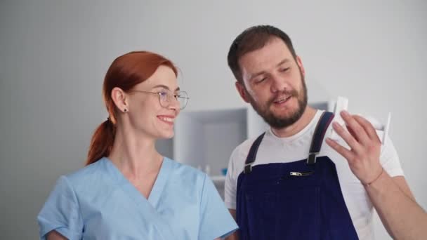 Portrait d'une jeune femme et d'un homme souriants serrant la main et discutant de l'installation d'une caméra de surveillance cachée dans un cabinet médical — Video