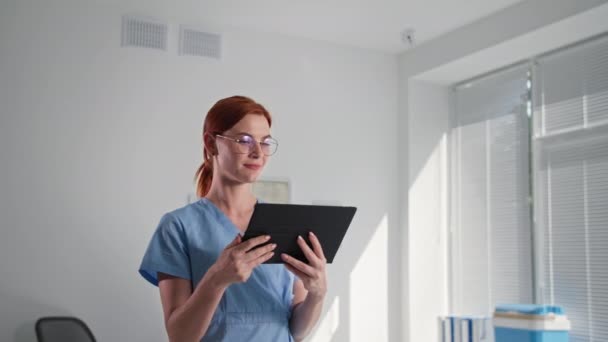 Caméra de surveillance cachée, médecin féminin portant des lunettes vérifie le fonctionnement de la vidéocaméra sans fil cctv à l'aide d'une application sur tablette numérique, montre la classe et regarde la caméra — Video