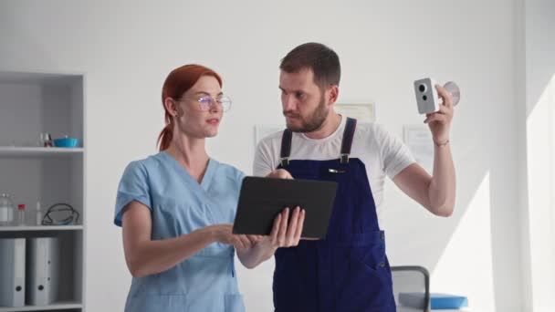 Muž bezpečnostní důstojník ukazuje mladou ženu provoz bezdrátové kamery na tabletu pomocí aplikace pro monitorování pracovního prostoru — Stock video