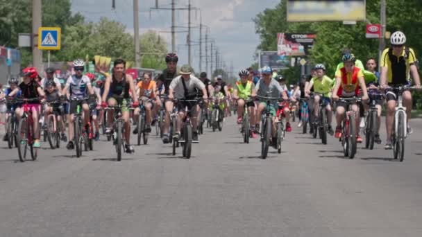 Херсон, Украина 10 августа 2021 года: толпа здоровых веселых подростков на велосипедах едет по дороге в солнечный летний день — стоковое видео