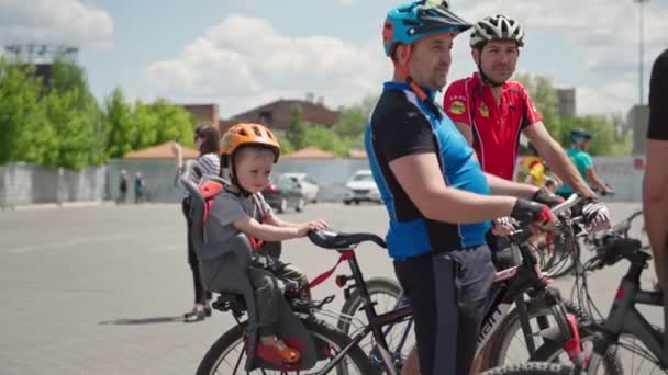 Kherson, Oekraïne 10 augustus 2021: Een meisje met een helm op zit in een fietsstoeltje terwijl ze met haar vader op fietstocht door de stad loopt — Stockvideo