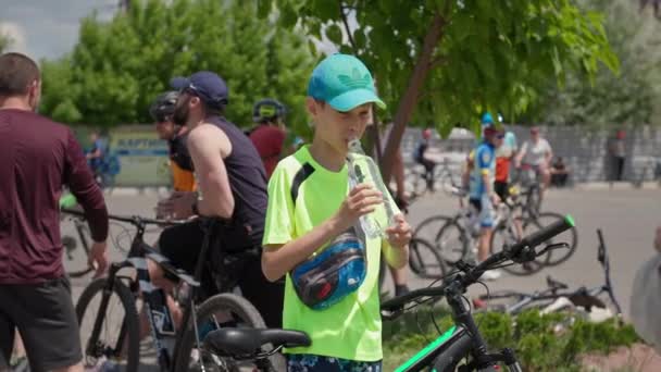 Kherson, Ucraina 10 agosto 2021: il ragazzo disseta e beve da una bottiglia di plastica contando l'acqua durante un giro in bicicletta — Video Stock