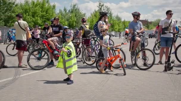 Kherson, Ukraine August 10, 2021: male child wearing cap glasses and protective vest shows thumb up background of group of people on bicycles — Stock Video
