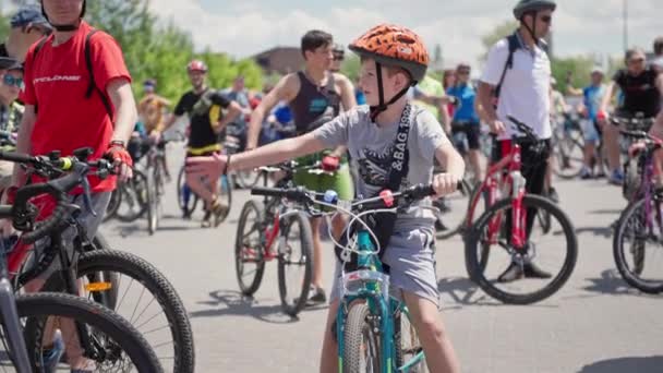 Chersoń, Ukraina 10 sierpnia 2021: Aktywne hobby, aktywne dzieciństwo, uroczy chłopiec w kasku uściska dłoń człowiekowi siedząc na tle rowerowym tłumu podczas przejażdżki rowerem po mieście — Wideo stockowe