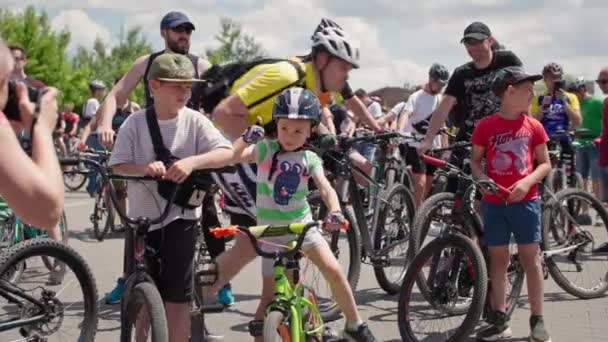 Kherson, Ukraina augusti 10, 2021: aktiv livsstil, liten pojke i hjälm på cykel fotograferas av kvinnliga förälder i bakgrunden av publiken av cyklister — Stockvideo