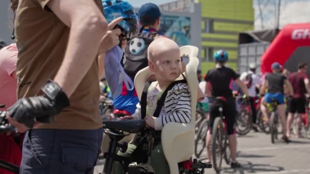 Kherson, Ucrania 10 de agosto de 2021: niñez activa, un niño pequeño y lindo sentado en un asiento para niños para montar en bicicleta con los padres — Vídeos de Stock