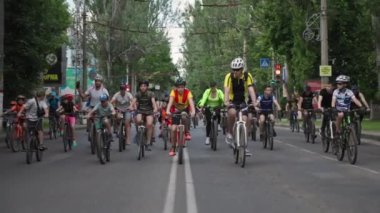 Kherson, Ukrayna 10 Ağustos 2021: ekolojik şehir ulaşımı, spor giyim ve kask giyen çocuklardan oluşan kalabalık ağaçların arka planında bisiklet sürerek aktif bir yaşam tarzı sürdürüyor.