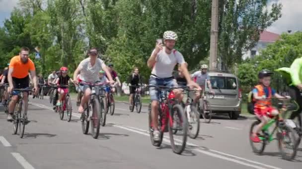 Kherson, Ukraine August 10, 2021: healthy people together with male and female children in helmets ride bicycles on road during bike ride — Stock Video