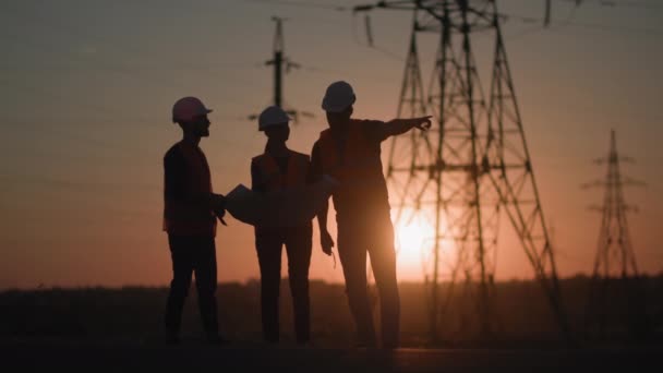 Jong team van mannelijke en vrouwelijke ingenieurs bespreken project van elektrische netwerken geven elkaar vijf en springen hun handen omhoog verheugen op succes achtergrond van zonsondergang, silhouet — Stockvideo