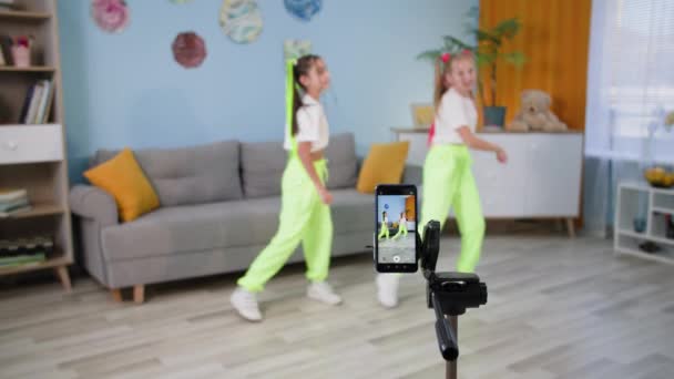 Sosyal ağlar için videoları cep telefonuyla çekerken evde dans eden kız arkadaşlar, çocuklar birbirlerine beş tane veriyor ve onay işaretlerini gösteriyorlar. — Stok video