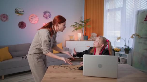 엄마는 온라인 게임을 하는 동안 딸의 컴퓨터 마우스를 떼어 내고 여자 아이는 반짝이는 색깔의 불빛을 배경으로 혀를 보여준다. — 비디오