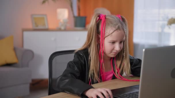 距離学習の子供はノートパソコンでビデオゲームをプレイし、ピンクのピグテールを持つ依存した女の子の肖像画は自宅でキーボードをクリックしてください — ストック動画
