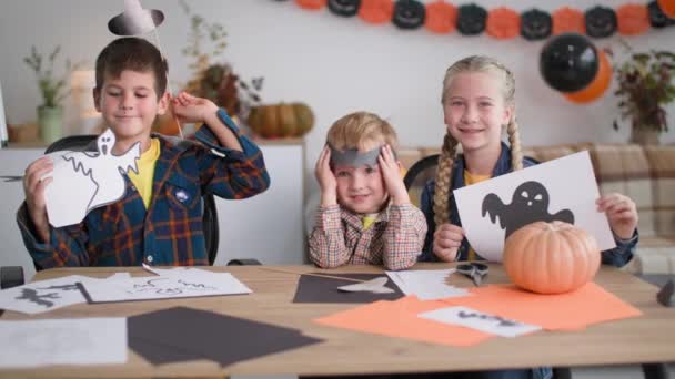 Enfance joyeuse, portrait d'amis heureux posant pour appareil photo avec des décorations d'Halloween, puis applaudissez leurs mains sur fond de guirlandes — Video