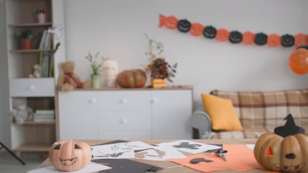 Kinderen verstoppen zich onder de tafel en springen dan uit en zeggen boo to camera, jongen in drakenkostuum en kinderen met pompoenmaskers schrikken tijdens Halloween viering — Stockvideo