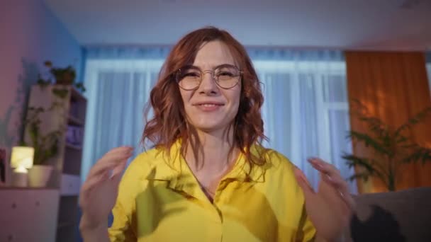 Kvinde med briller glæder sig over at vinde og vinde online quiz, mens du sidder på laptop i stuen om aftenen – Stock-video
