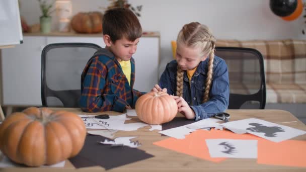 Halloween, children cut out pictures to decorate the room and draw a pumpkin face with a felt-tip pen to celebrate the autumn holidays — 图库视频影像