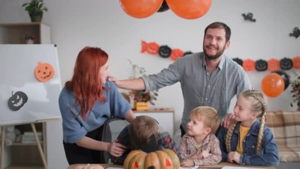 Familia feliz amistoso, los padres y los niños preparan alegremente dibujos decorativos para decorar la habitación, sonreír y mirar a la cámara y mostrar signo de boo, concepto de Halloween — Vídeos de Stock