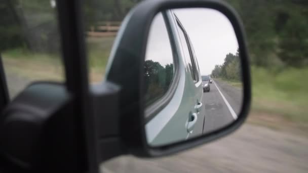 View from rear-view mirror, roadway with cars is reflected in mirror while driving around city, close-up — Stock Video