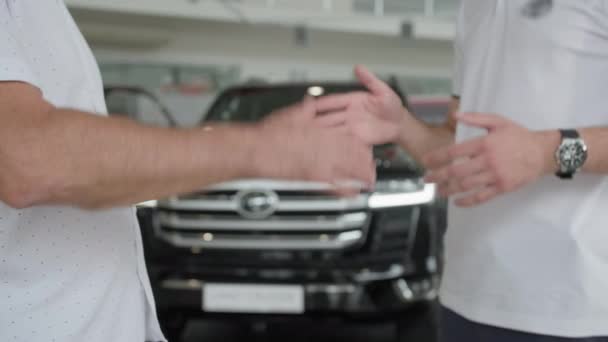 Serviço de carro, cliente masculino satisfeito aperta as mãos firmemente confirmando a oferta de carro no showroom do carro — Vídeo de Stock