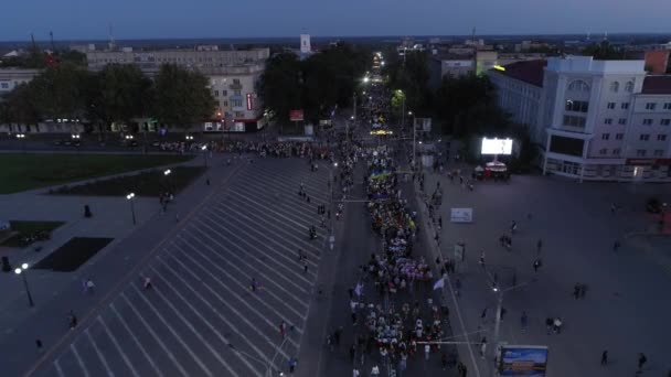 KHERSON, UKRAINE - 7 septembre 2021 Festival Melpomene de Tavria, foule de personnes avec le drapeau jaune-bleu de l'Ukraine marchent le long de la rue principale de la ville en soirée, aérien — Video