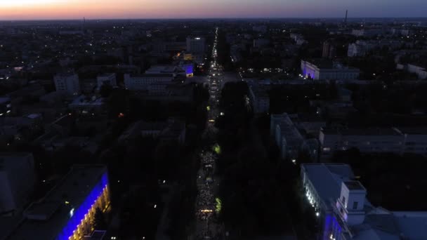 KHERSON, UKRAINE - 7 septembre 2021 Festival Melpomene de Tavria, vue de la ville la nuit pendant le défilé festif et foule de personnes marchant le long de la rue principale de la ville, aérien — Video