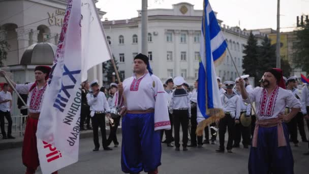 KHERSON, UKRAINE - 7 septembre 2021 Festival Melpomene de Tavria, groupe de personnes en costumes cosaques avec des drapeaux dans leurs mains se tiennent derrière la foule pendant le festival de la ville — Video