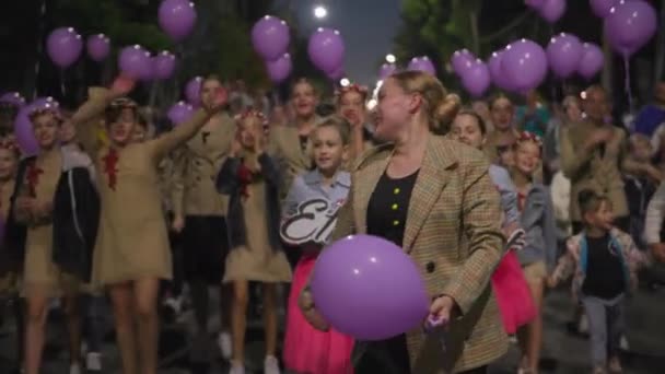KHERSON, UKRAINE - 7 septembre 2021 Festival Melpomene de Tavria, joyeux groupe féminin avec des ballons violets marcher sur la route et chanter des slogans pendant le défilé de la ville dans la soirée — Video